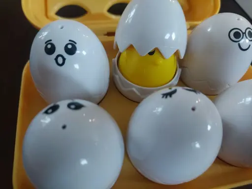 A kids toy that a carton of six toy eggs with faces. The top left one is pogging.