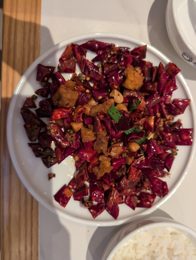 A plate full of chilli with a few peanuts and pieces of chicken in between