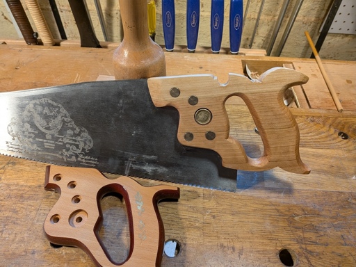 A panel saw with a vintage-looking handle and the stock handle it replaced.